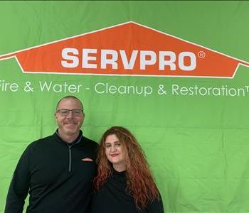 Male and female owners standing in front of green SERVPRO sign