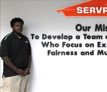 Tech standing in front of our mission statement