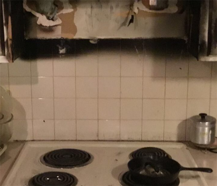 A stove that has caught fire with black soot and burned ash on everything