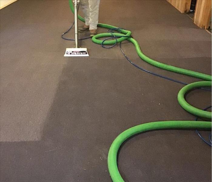 SERVPRO employee using one of our water extractors to remove water from carpet