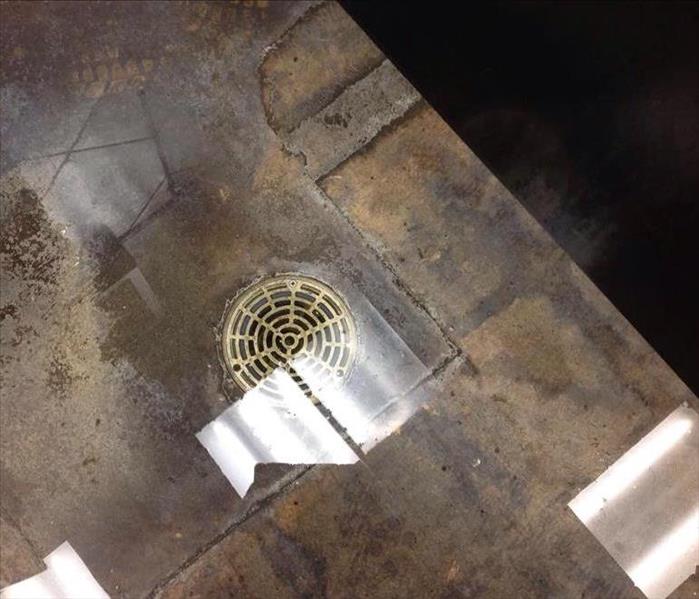 Large water puddle in restroom over drain that isn't working